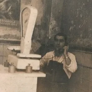 Archivo familiar: hombre atendiendo el teléfono junto a una balanza antigua